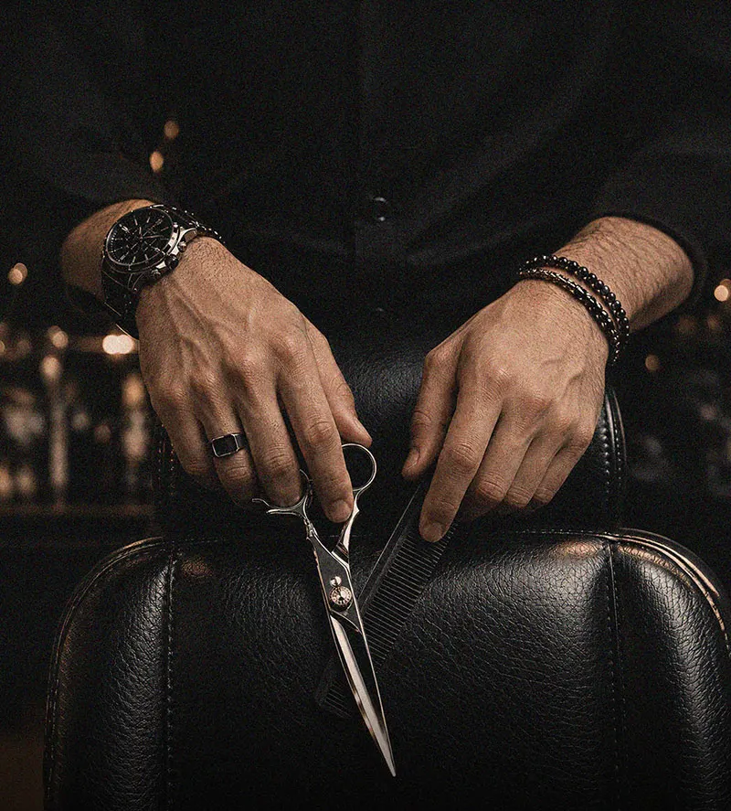 Barber holding scissors and a comb over a leather chair